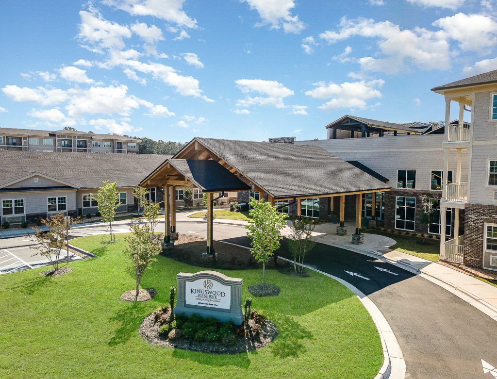 Welcome to Kingswood Reserve Senior Living, showcasing a beautifully landscaped entrance with a grand portico, modern architecture, and inviting green spaces. Your ideal senior living community.