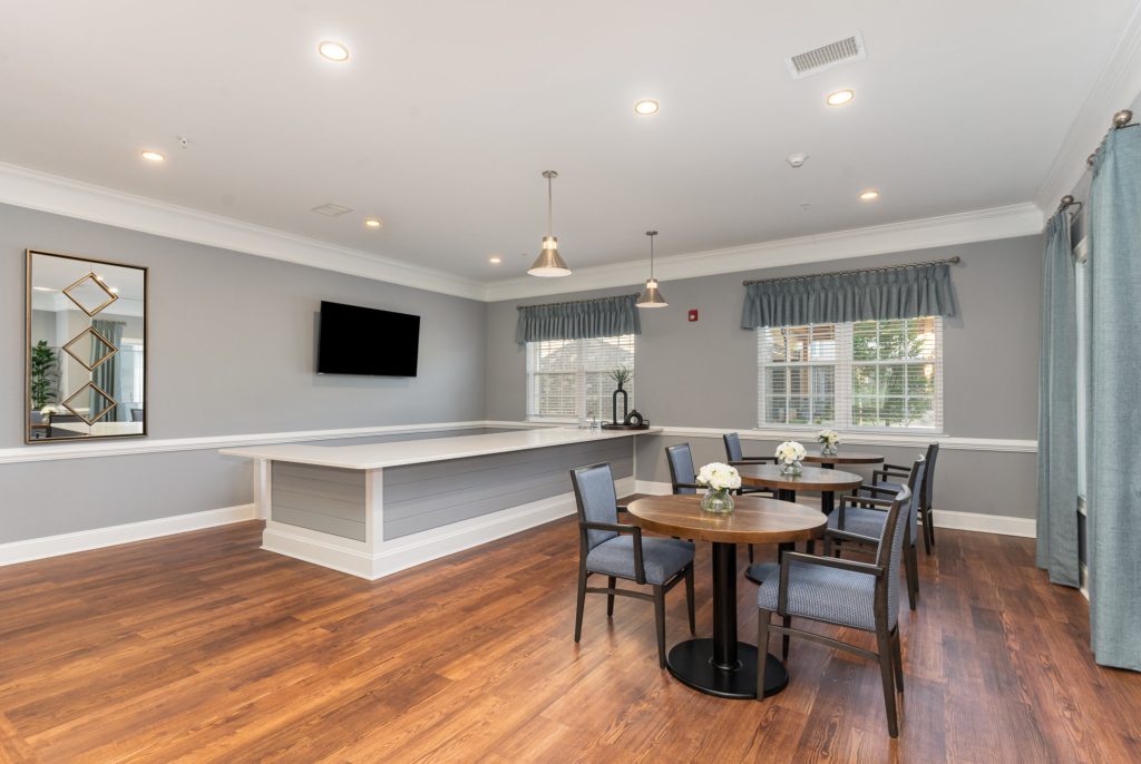 Bright and spacious community room with a bar area, round dining tables, and contemporary decor. Perfect for social gatherings and events.
