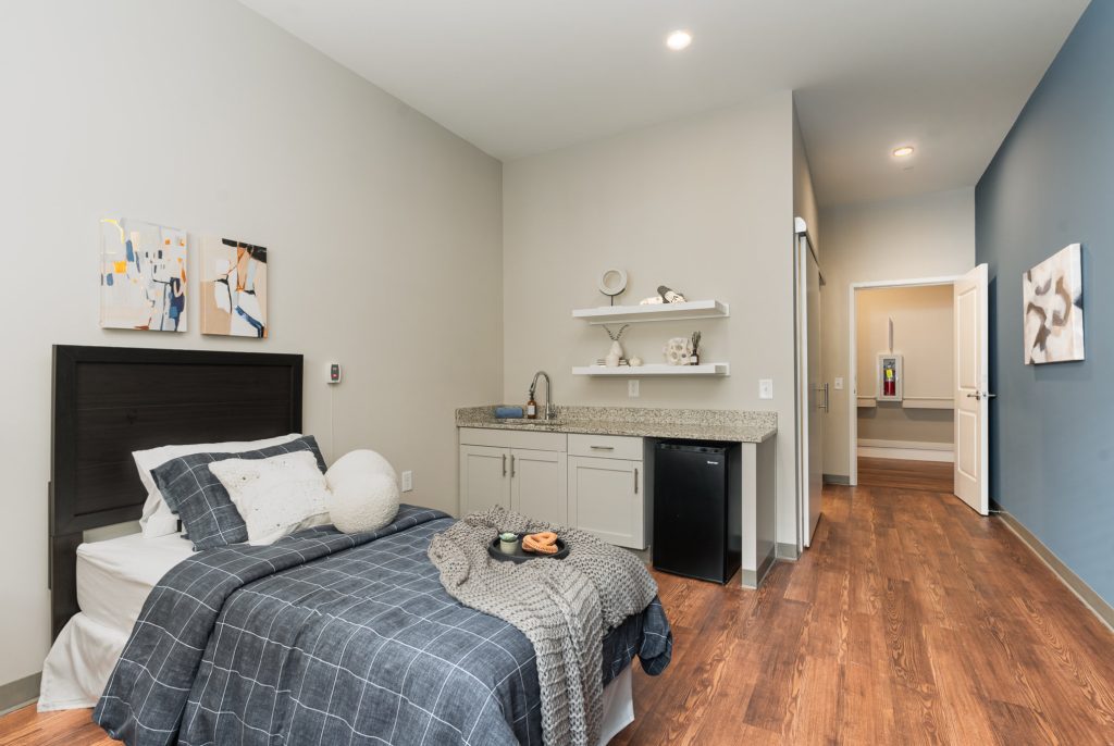 Bright bedroom with an in-room sink, ample shelving, and modern decor. Offers a functional and cozy living space.