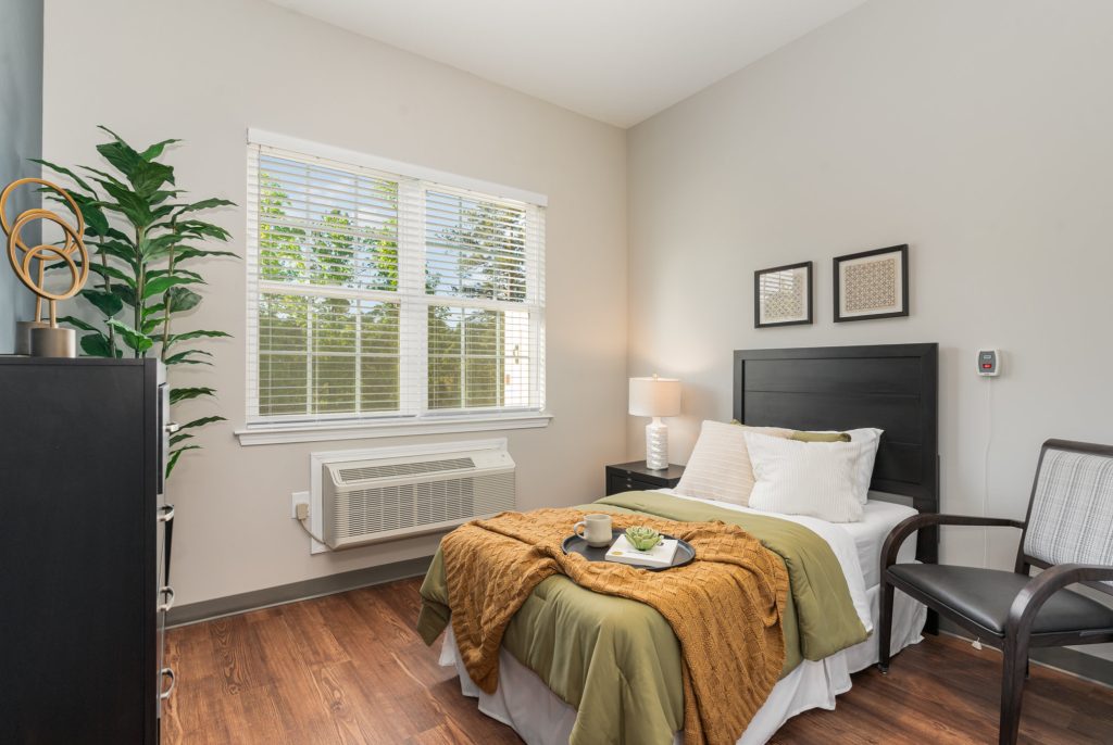 Cozy and compact bedroom with stylish decor, featuring a comfortable bed, dresser, and large window for natural light.