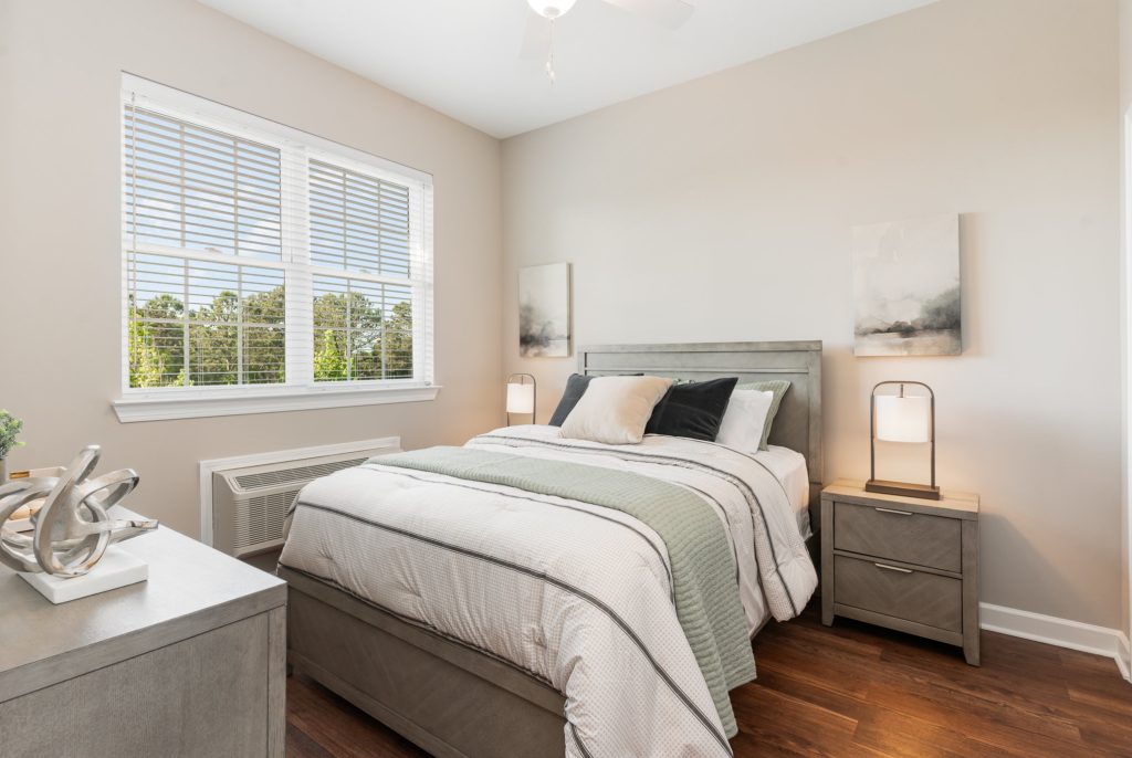 Bright and cozy bedroom featuring a large window for natural light, modern decor, and comfortable furnishings. Ideal for a relaxing retreat.