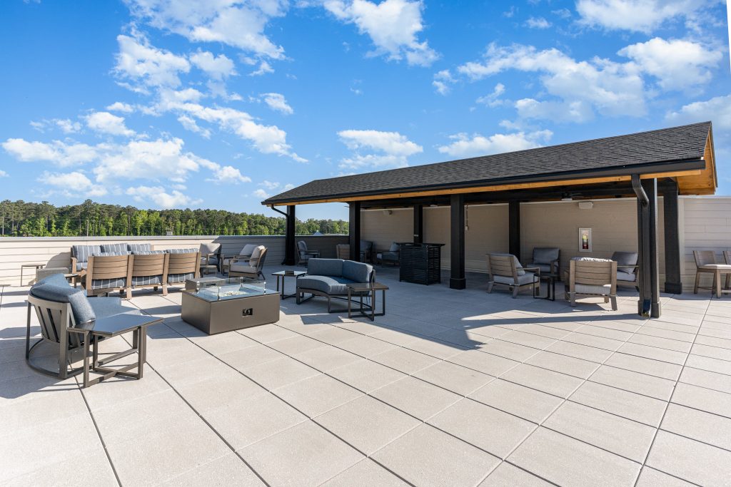 Modern rooftop lounge area with covered seating and fire pits, providing a comfortable space for relaxation and socializing with stunning views.