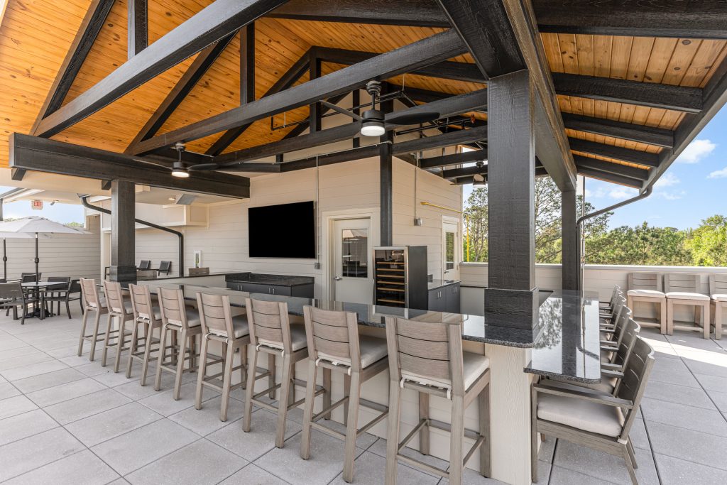 Stylish outdoor bar and lounge area featuring a large bar counter, comfortable seating, and modern amenities. Perfect for social gatherings and events.