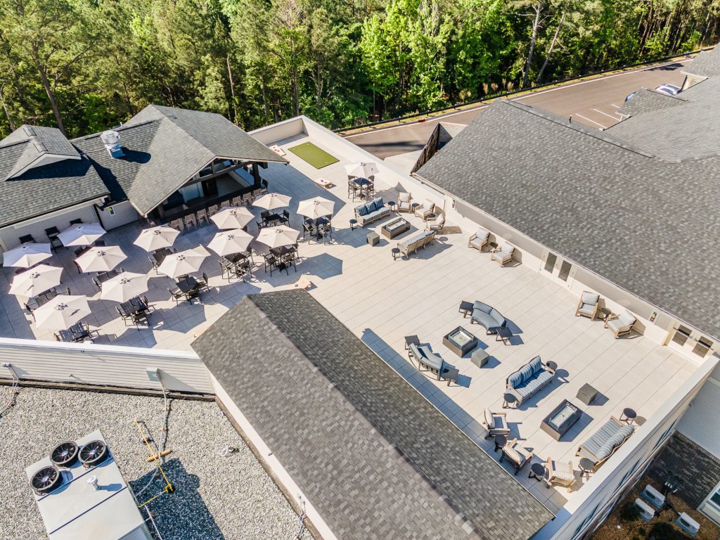 Bird’s-eye view of Kingswood Reserve’s spacious rooftop patio area with ample seating, umbrellas, and a cozy lounge setup. Perfect for outdoor gatherings and relaxation.